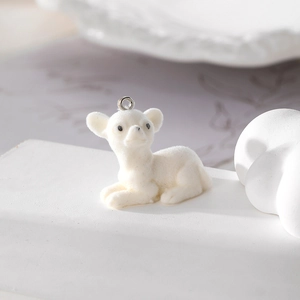 Macro shot of white flocked baby deer pendant with silver metal ring on white stone base