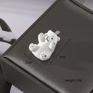 Close-up of white flocked polar bear pendant with metal ring on dark jewelry box