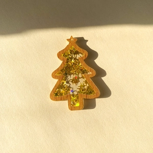 Detail of wooden Christmas tree pendant with shimmering gold star sequins and acrylic layer