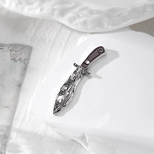 Macro shot of silver alloy dagger pendant with damascus pattern and brown enamel handle