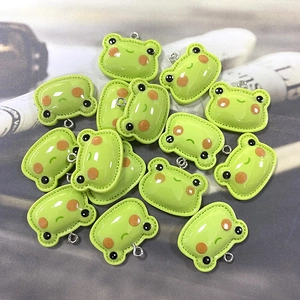 Macro view of cute green resin frog charms with silver metal rings for DIY jewelry