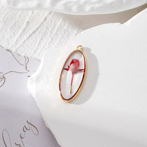 Macro detail of red rose bud preserved in clear resin with a gold oval metal frame