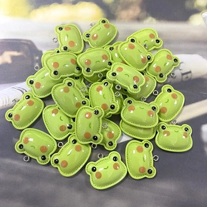 Macro shot of bulk resin green frog charms with silver metal rings for DIY jewelry craft