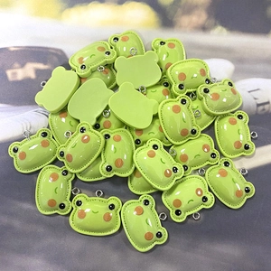 Close-up of assorted resin green frog pendants with metal rings for DIY jewelry making
