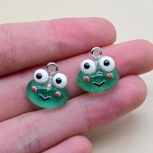 Detail von süßen grünen Froschanhängern aus Harz mit Metallringen für DIY-Schmuck