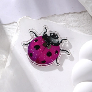 Macro detail of purple gradient acrylic ladybug pendant with glitter on stone
