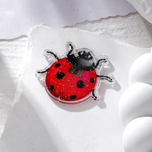 Macro shot of red glitter acrylic ladybug charm for DIY earrings and necklaces