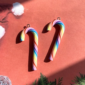 Close-up of rainbow striped candy cane pendants with metal rings on festive red background