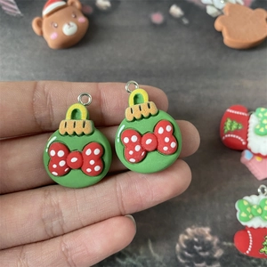 Détail d'un pendentif boule de Noël en résine avec nœud rouge et crochet argent