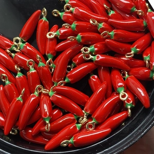 Macro shot of red chili charms for jewelry making with green stems and gold loops