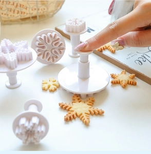 Action shot showing the spring-loaded snowflake cookie cutter stamping dough shapes