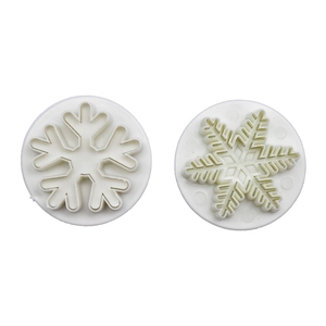 Macro view of white snowflake cookie cutters showing intricate embossed patterns and details