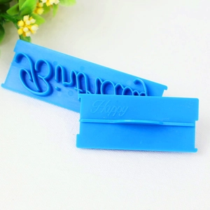 Close-up of blue Happy Birthday cursive stamp tools for fondant cake decoration