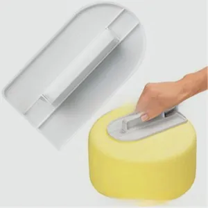 Macro shot of white plastic cake scraper tool with wide handle for smoothing fondant