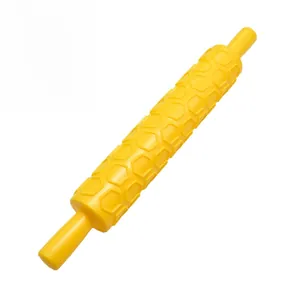 Detail of yellow plastic rolling pin with textured honeycomb pattern for fondant DIY baking