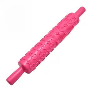 Detail of pink rolling pin featuring embossed heart and star patterns for baking cake fondant