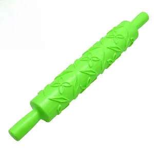 Close-up of a green fondant rolling pin featuring detailed floral and star embossing patterns