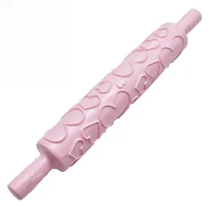 Detailed view of pink plastic rolling pin with embossed heart patterns for fondant cake DIY