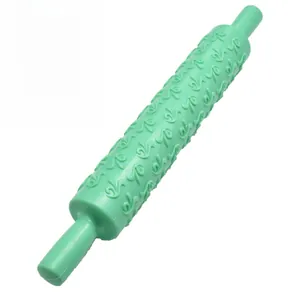 Detail of green plastic rolling pin with embossed floral pattern for fondant and cake DIY