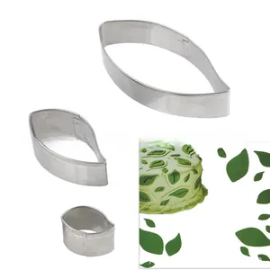 Macro shot of stainless steel leaf-shaped fondant cutters with a cake decoration scene