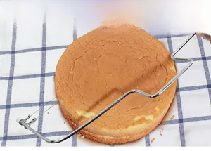 Close-up of double-wire stainless steel cake slicer cutting a layered sponge cake