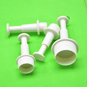 Set of four white plastic plunger cutters for fondant and cookie dough on green background