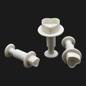 Detailed macro view of three white heart-shaped spring loaded fondant plunger cutters