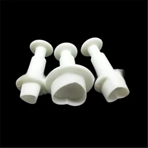 Detailed view of three white heart-shaped spring-loaded cookie fondant plungers