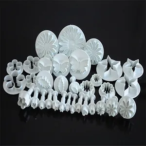 Detail view of white food-grade plastic fondant plunger cutters in various floral shapes
