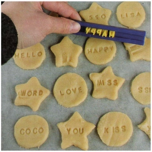 Detail of DIY cookie stamper pressing custom letters into yellow dough on baking paper