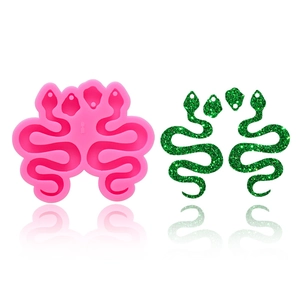 Detailed pink silicone snake mold and finished green glitter resin earrings on white