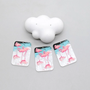 Détail de trois pendentifs flamant rose rectangulaires en acrylique avec motifs et trous