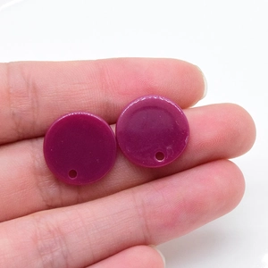 Primo piano di un ciondolo circolare in acrilico viola con foro per orecchini fai-da-te