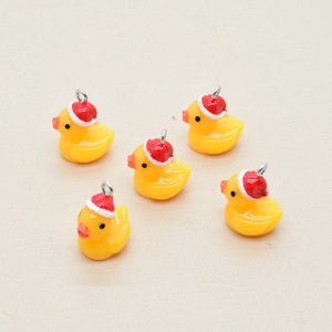 Close-up of five resin yellow duck pendants wearing red Christmas hats for DIY jewelry
