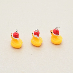 Macro shot of resin yellow duck charms with Christmas hats for DIY jewelry crafting