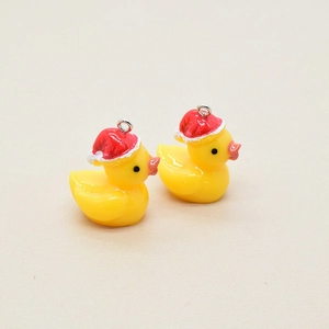 Close-up of cute resin Christmas yellow duck pendants with red hats for DIY jewelry