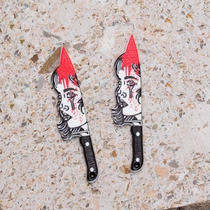 Macro shot of gothic acrylic knife charms featuring bloody face art for DIY jewelry
