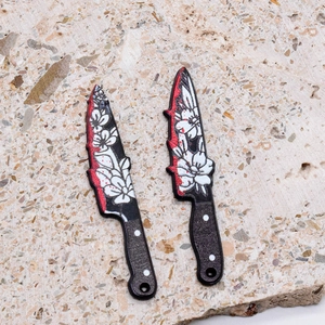 Macro detail of acrylic Halloween dagger charms with floral patterns and blood splatters