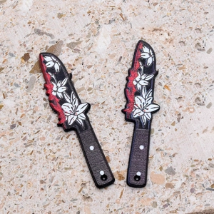 Detail of acrylic Halloween knife pendants with lily flower patterns and red blood splatters