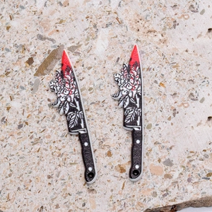 Detailed macro view of acrylic bloody knife pendants with floral patterns and blood splatters