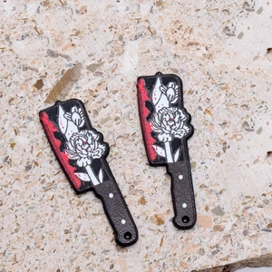 Macro detail of acrylic Halloween knife charms with gothic floral patterns and blood splatters