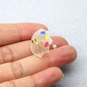 Dettaglio mini ciondolo a ombrello in acrilico rosa con cuori e perla per gioielli fai da te