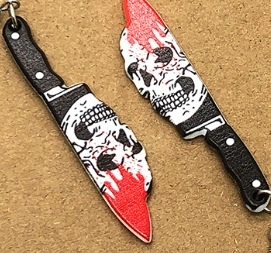 Detail of acrylic Halloween dagger charms with skull pattern and blood splatter effects
