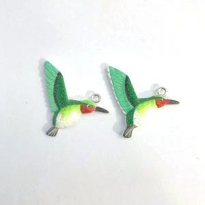 Detail of colorful hummingbird resin pendants with vivid green wings and 3D textured carving