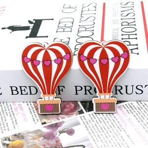 Close-up of heart hot air balloon wooden charms on book pages for DIY jewelry crafts