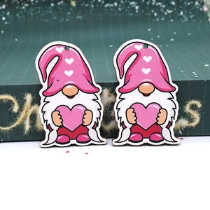 Detail of two pink gnome wooden charms with heart hats and white beards on table