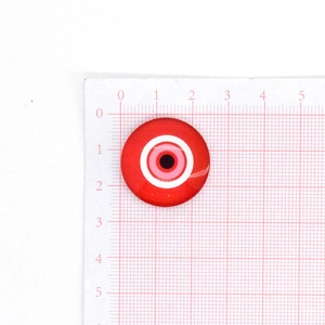 Vista dettagliata di un cabochon in vetro rosso Evil Eye da 25 mm su scala graduata