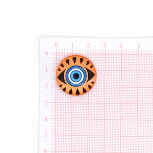 Dettaglio del cabochon in vetro Occhio del Male arancione 22mm su griglia graduata