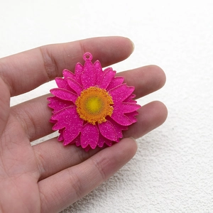 Colgante de margarita 3D rosa con centro amarillo y purpurina fina sostenido a mano