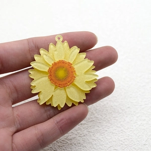 Detalle de colgantes de girasol con purpurina amarilla y centros naranjas para joyas DIY